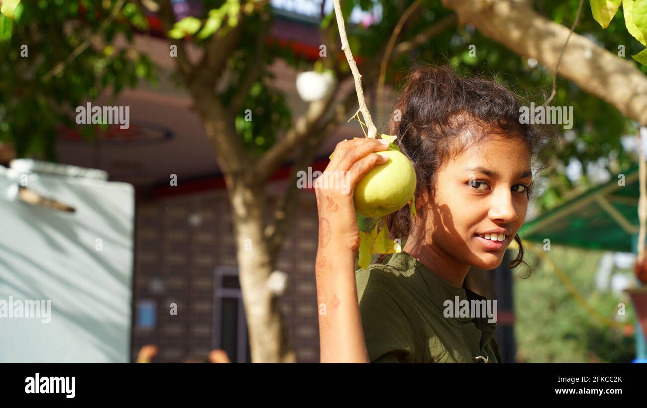 30 April 2021, Jaipur, Rajasthan, India. Cute girl with Bael or Bilv fruit. Asian girl holding bilv fruit in her hand. Stock Photo