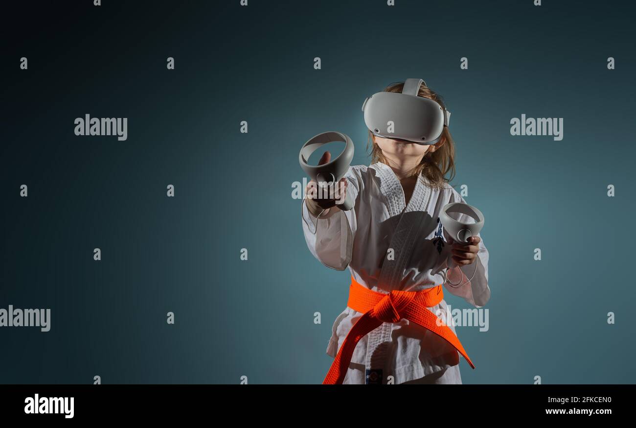 Studio Portrait of young caucasian girl in karate uniform playing video
