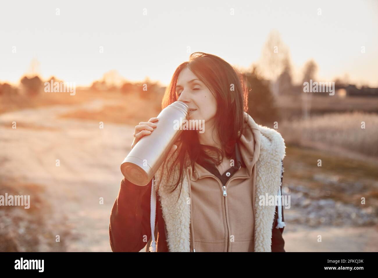 Young woman with flask outside at evening night. Leisure time outside concept. Staying motivated concept. Mental and physical health and abilities concept. High quality photo Stock Photo