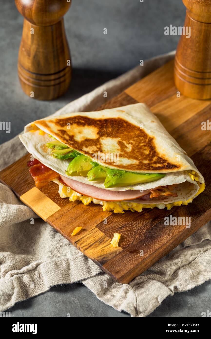 Homemade Trendy Egg Tortilla Breakfast Sandwich with Ham and Avocado Stock Photo