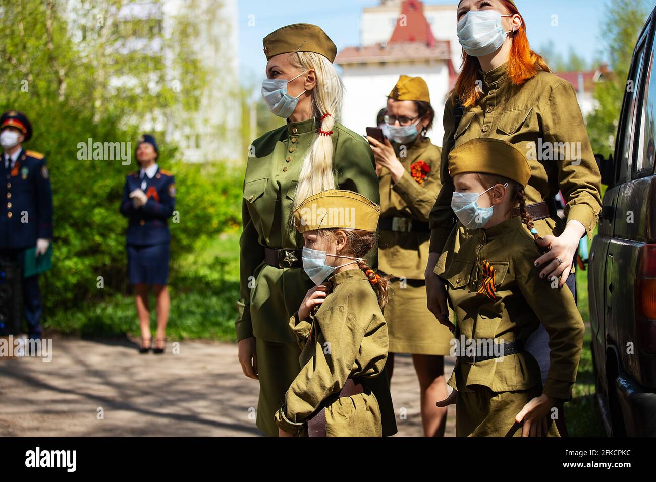 a little girl in a military uniform and a medical mask on her face. a solemn costumed procession on a patriotic military holiday. holiday during the q Stock Photo