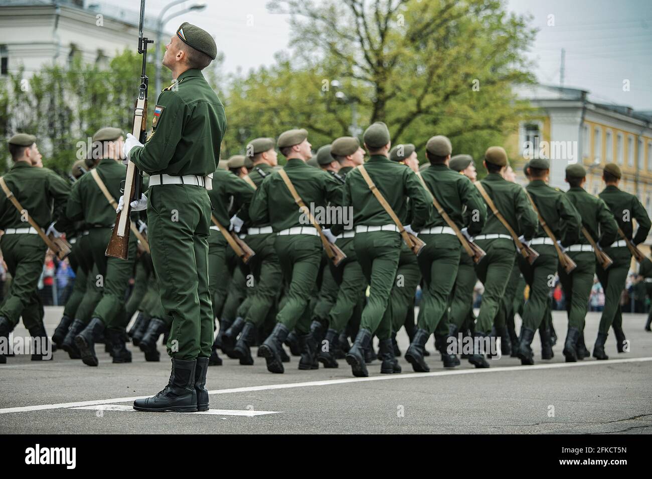 military holiday in city, parade of armed forces of country a solemn March through streets of city, soldiers in uniform clearly stamping step in colum Stock Photo
