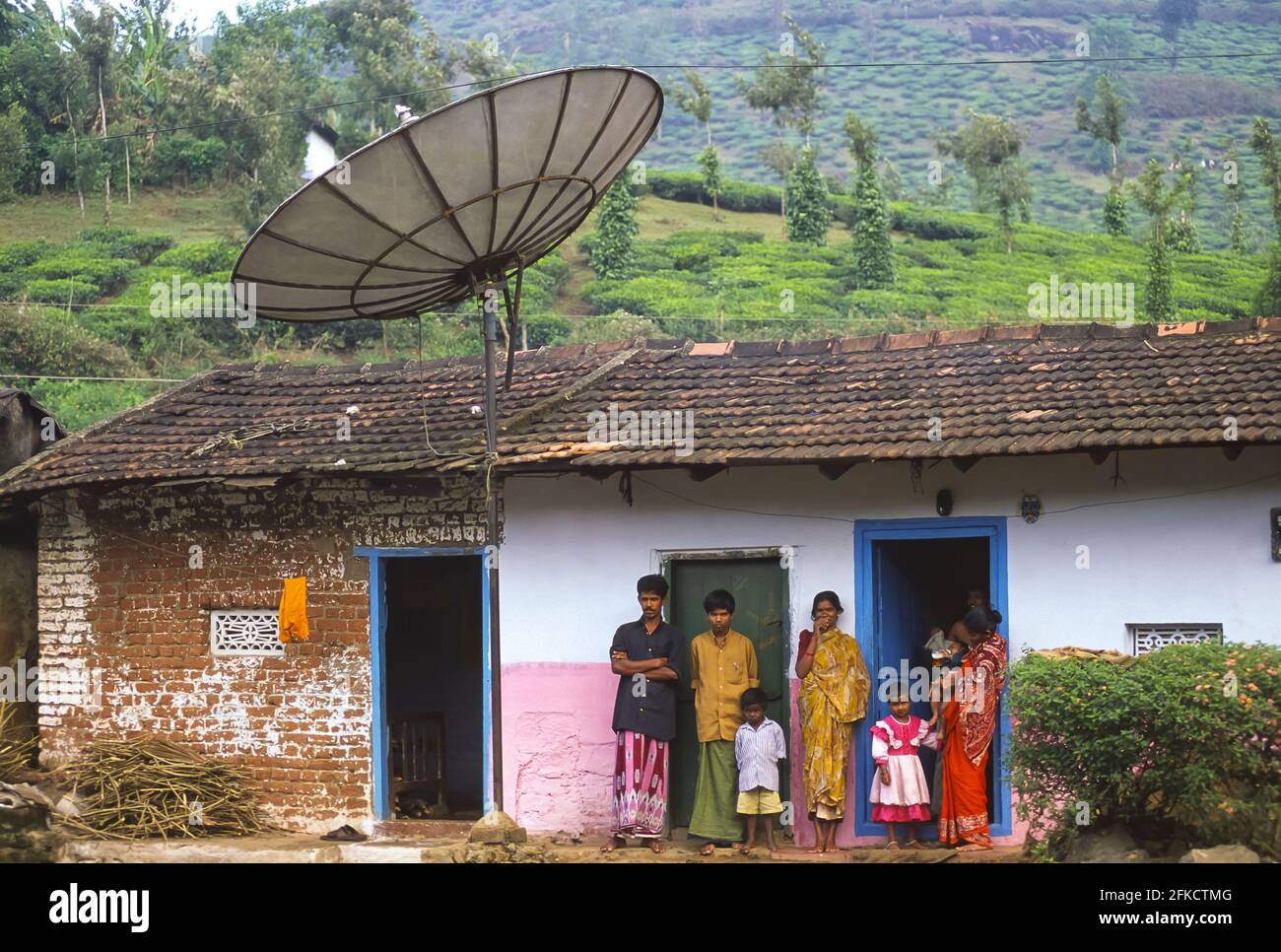 KERALA, INDIA - Family rents viewing time to neighbors on their satellite television in the Western Ghats mountains, Kerala State, India. Pepper and tea grow behind their home. Stock Photo