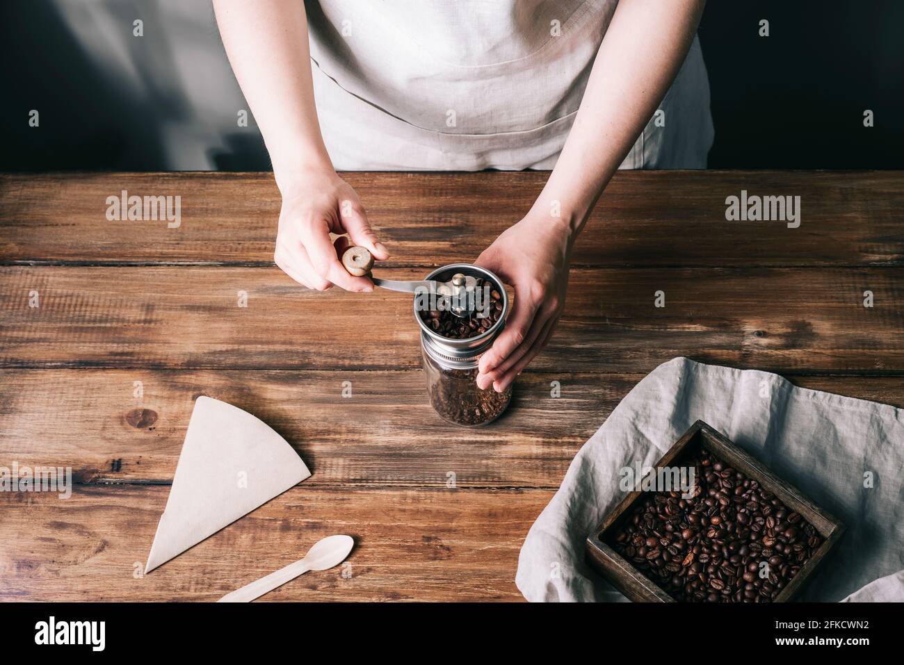 Grinding coffee in a metal and glass coffee grinder on a wooden table Stock Photo
