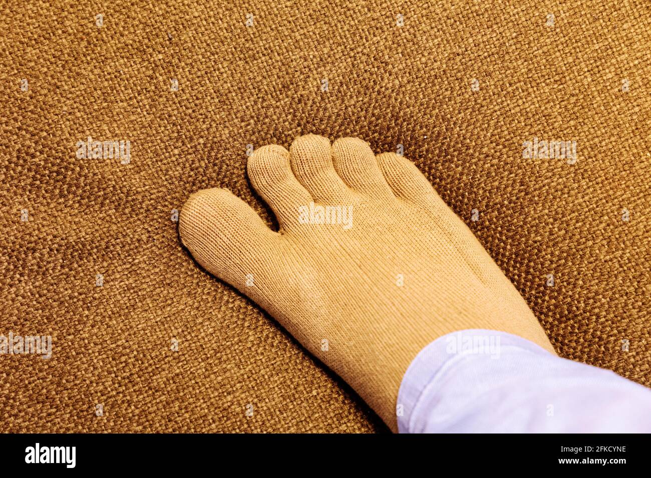 Healthy finger socks wearing foot on sofa in top view close up image. Stock Photo