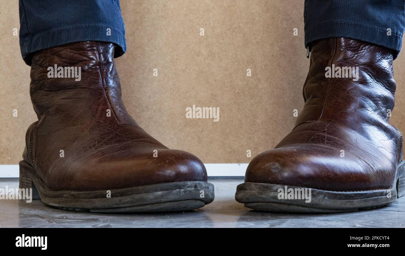 Close up of Leather boots wearing feet facing each other. Stock Photo