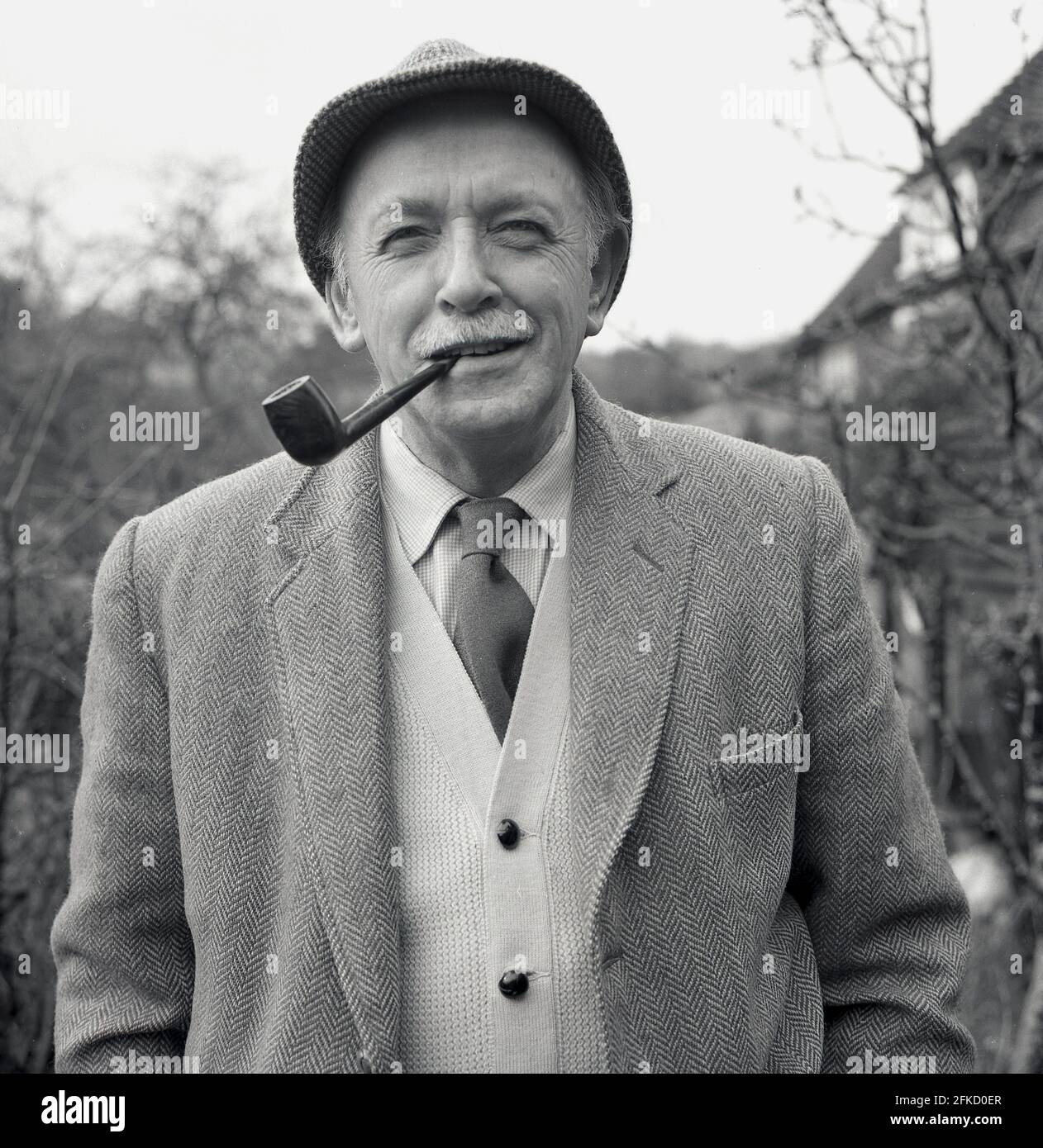 1950s, a portrait of Brian Vesey-Fitzgerald, a naturalist and writer of books on nature, birds and dogs. Also editor of The Field magazine, he was a descendant of the Vesty-Fitzgeralds, a famous Ango-Irish family whose members became MPs in both British and Irish governments. Born in 1905 in Wrexham, Denbighshire, Wales, as Brian Percy Seymour Vesey Fitzgerald, like many of his generation, he loved his tobacco and is seen here with his pipe and wearing traditonal country clothing of a tweed jacket and tie with a cardigan and hat. He was an authority on the history of Gypsies in Britain. Stock Photo