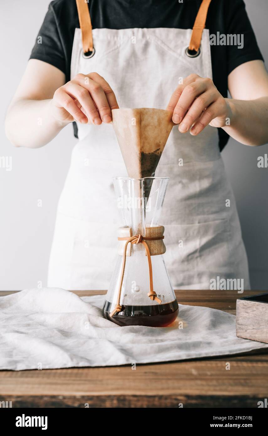 Hands removing the paper filter from the manual glass coffee maker with