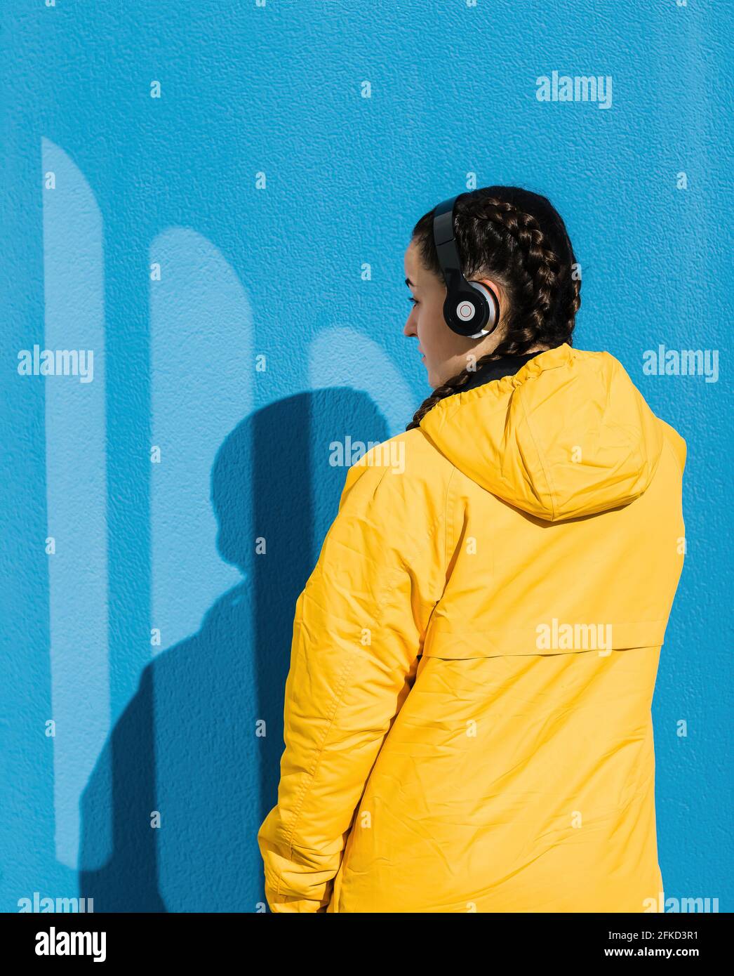 Teenage girl wearing yellow coat and headphones Stock Photo
