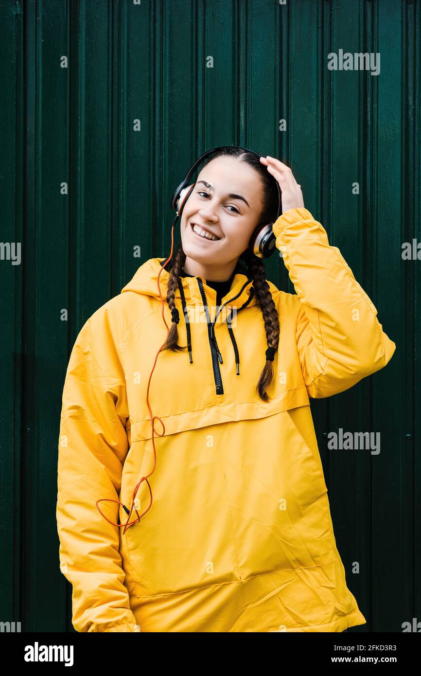 Portrait of teenage girl wearing yellow coat and headphones Stock Photo