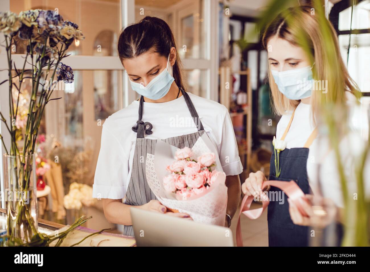 Flower shop workers in protective masks decorate a bouquet Stock Photo