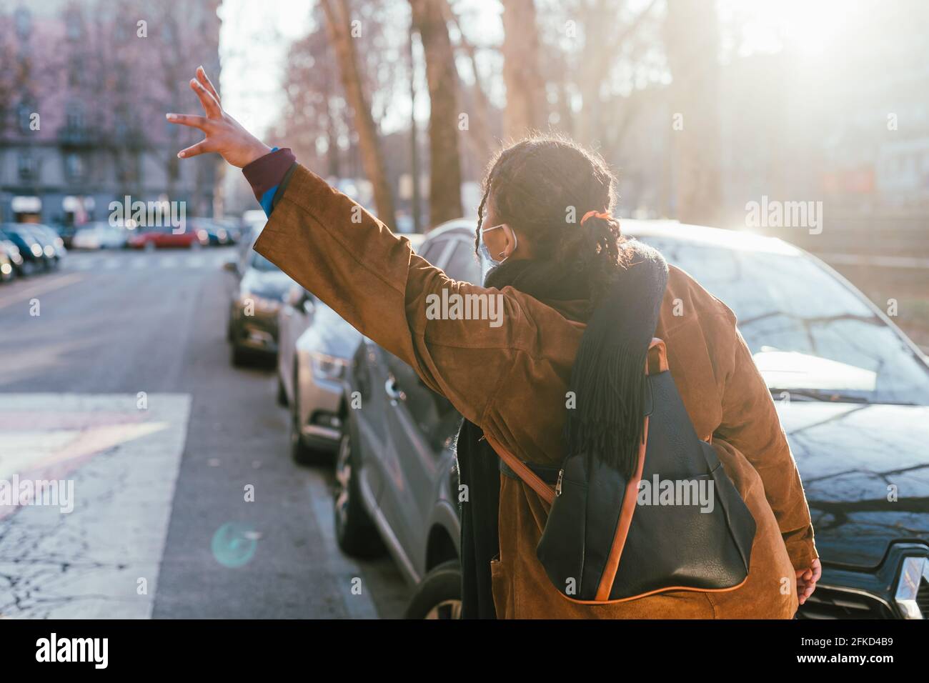 Rear view of woman hailing cab on street Stock Photo - Alamy