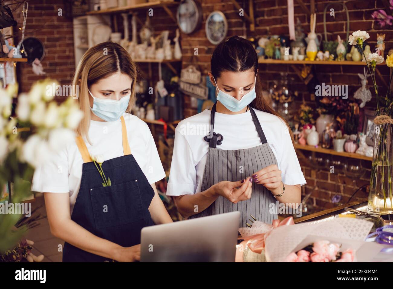 Flower shop workers in protective masks using laptop. Stock Photo