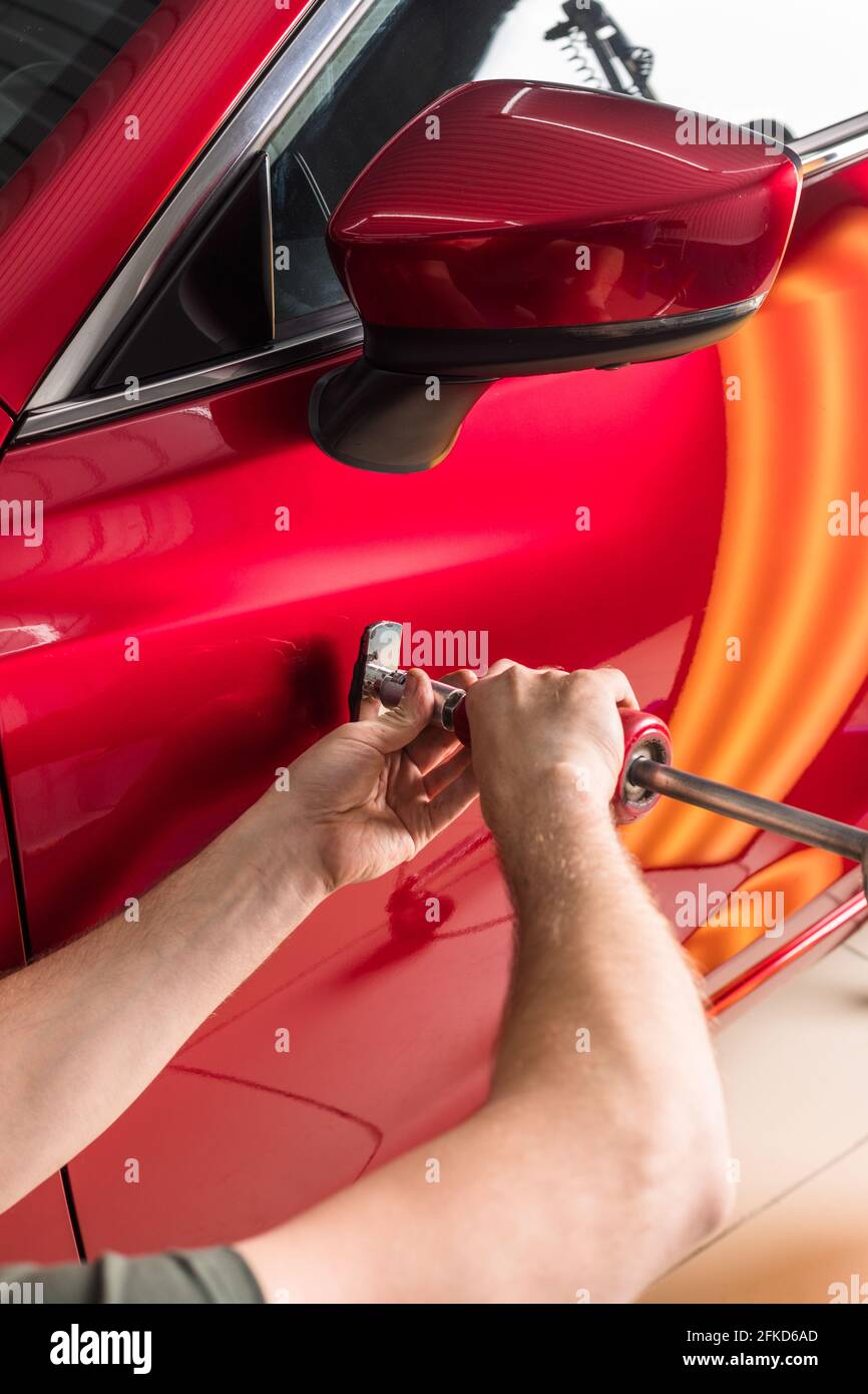 The technician removes dents on the car using the method without