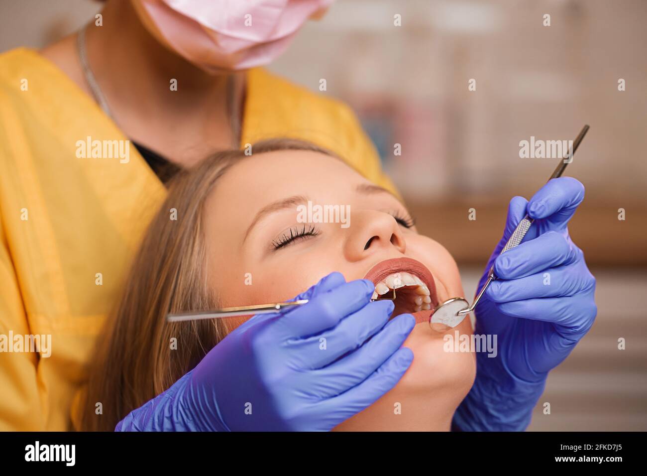 Beautiful blonde patient at the dentist. The young women's teeth being checked, examined and treated by a female dentist with the help of special medi Stock Photo