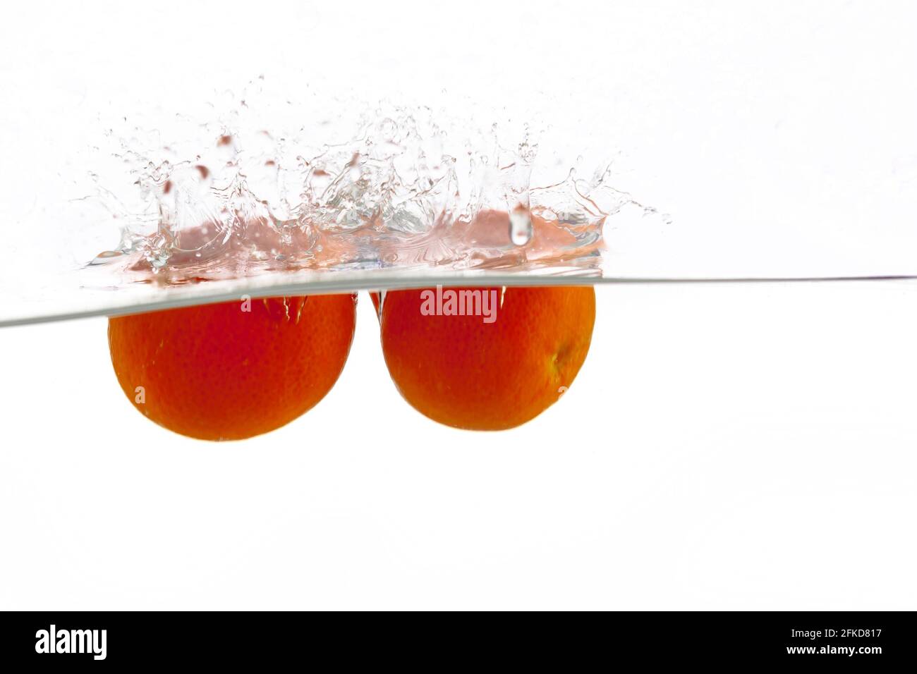 two tangerines falls into the water on a white background, isolate, place under the text Stock Photo