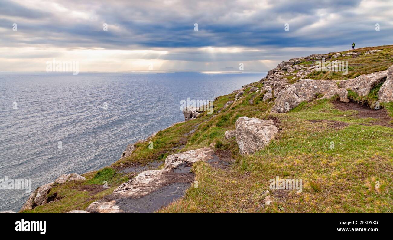 A close up of a hillside next to a body of water and a lighthouse Stock