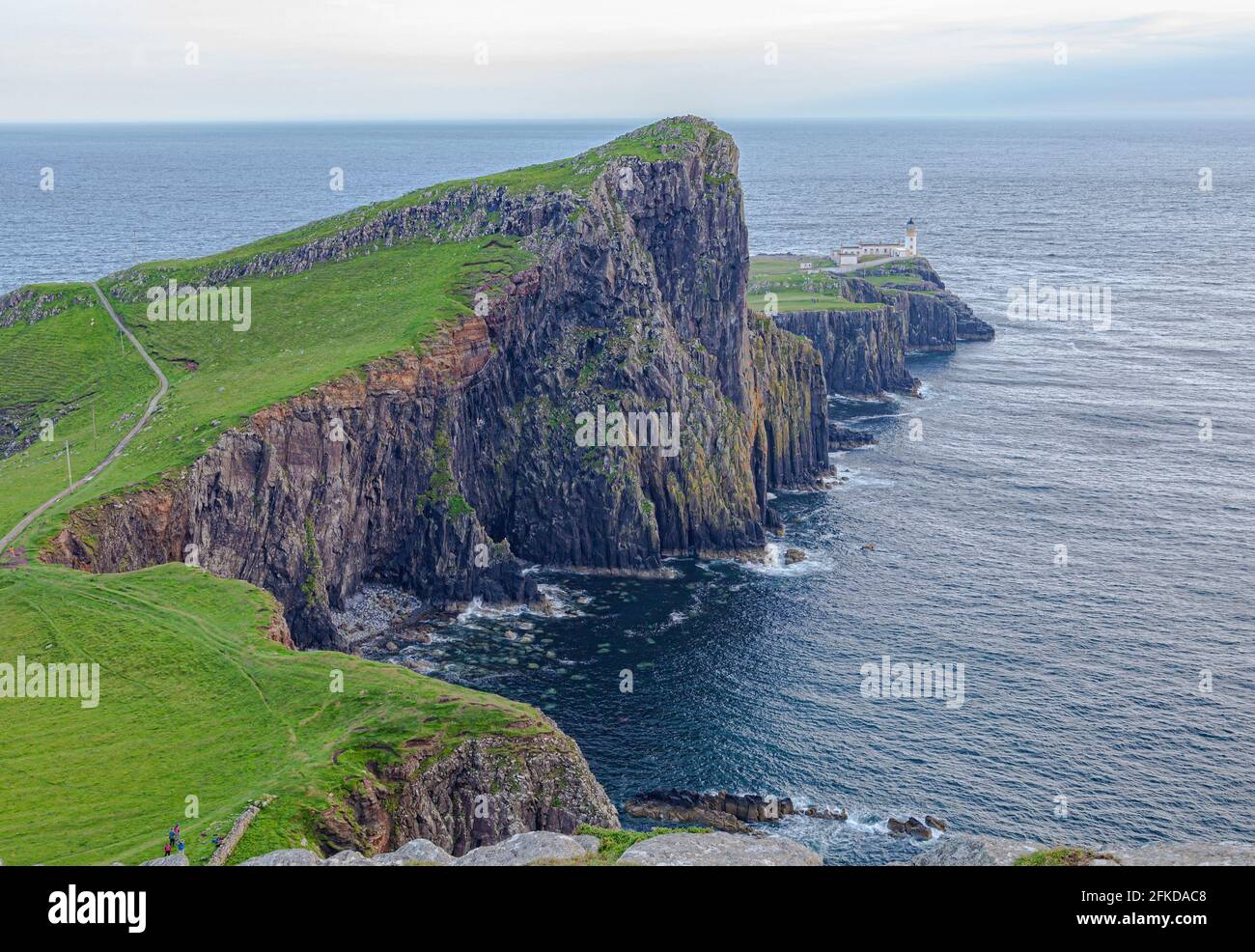 A close up of a hillside next to a body of water and a lighthouse Stock