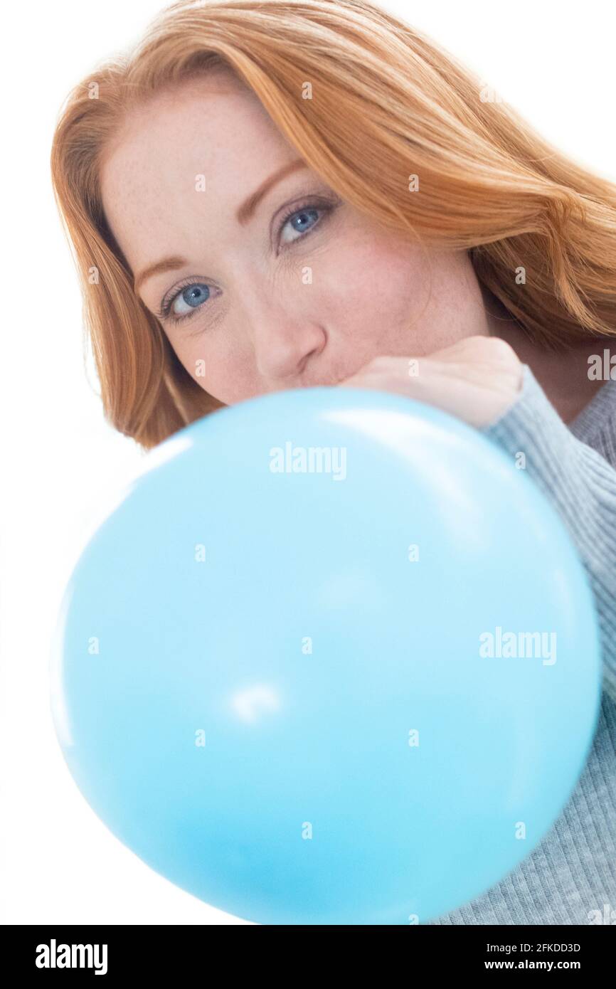 Woman blowing up balloon Stock Photo
