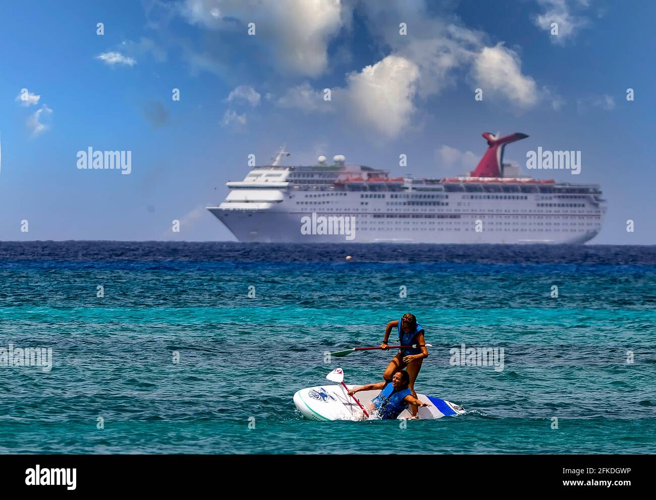 Paddling out in. the Caribbean Sea as a giant Cruise Ship comes into George Town, Cayman islands Stock Photo