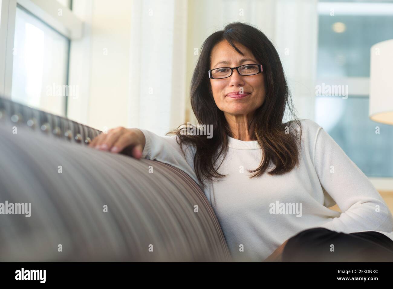 Portrait of a beautiful mature woman sitting on the sofa Stock Photo ...