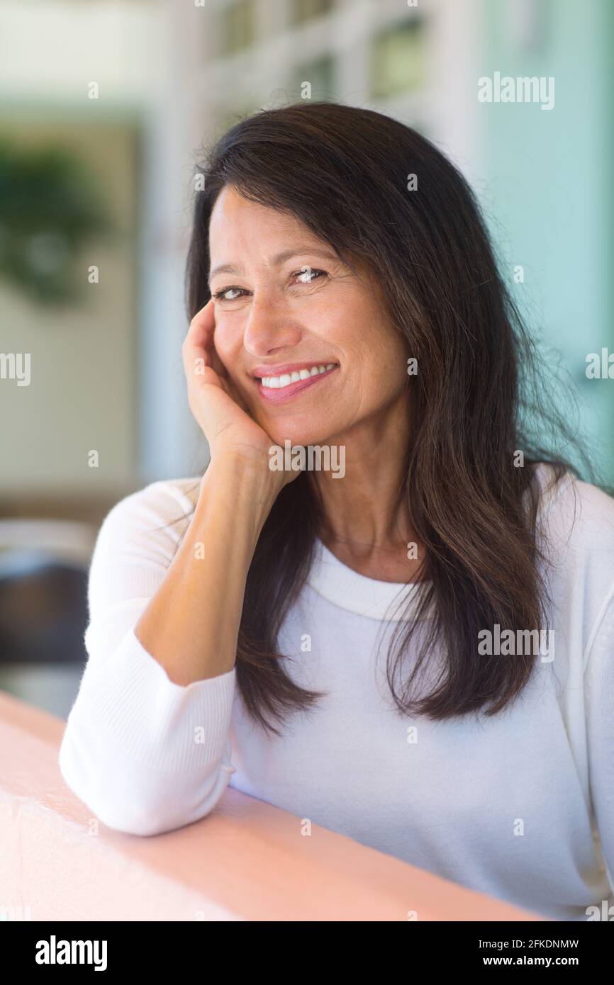 Portrait of a beautiful mature woman sitting on the sofa Stock Photo ...