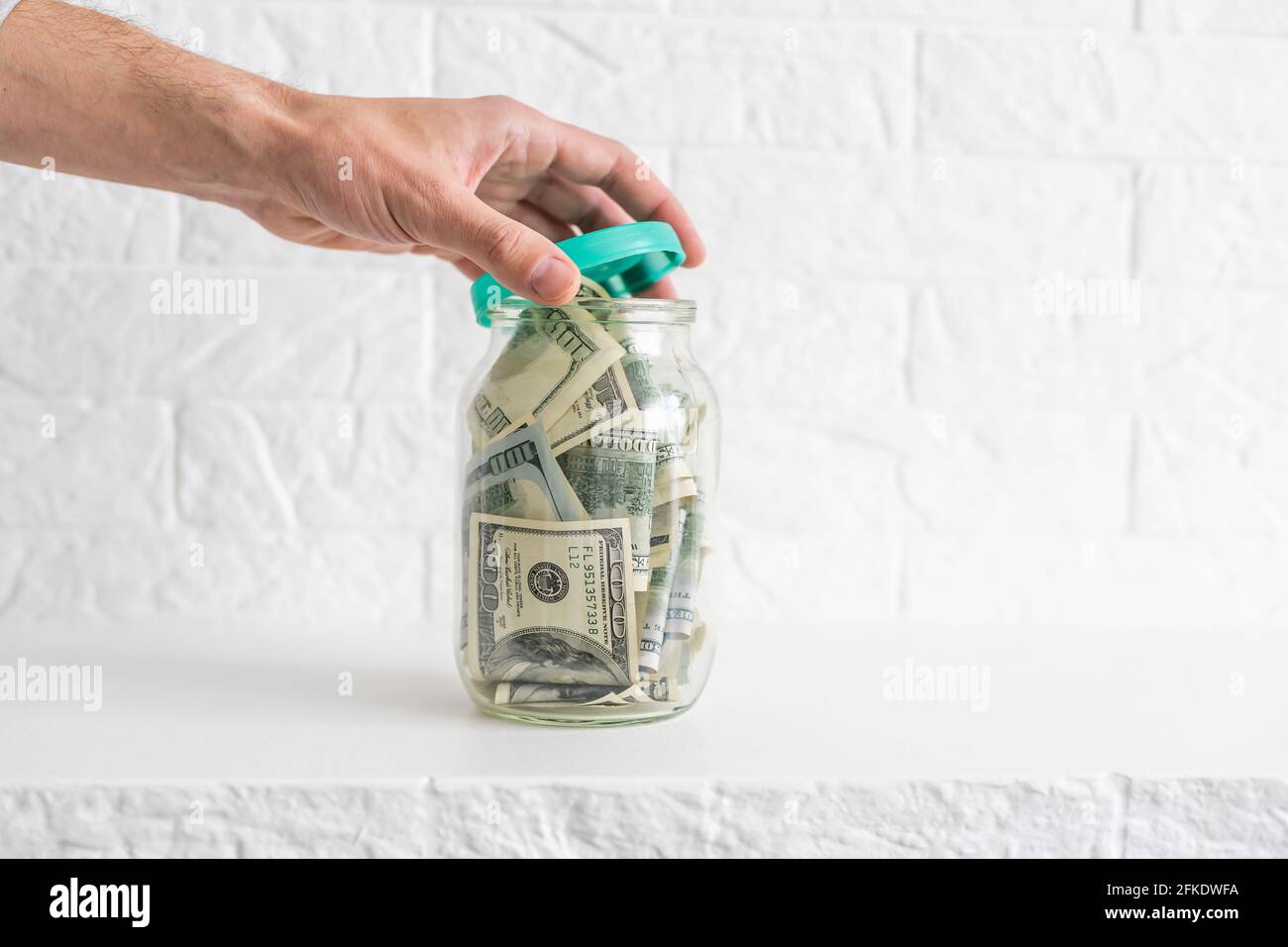 Many dollars bank notes in a glass jar isolated on white background ...