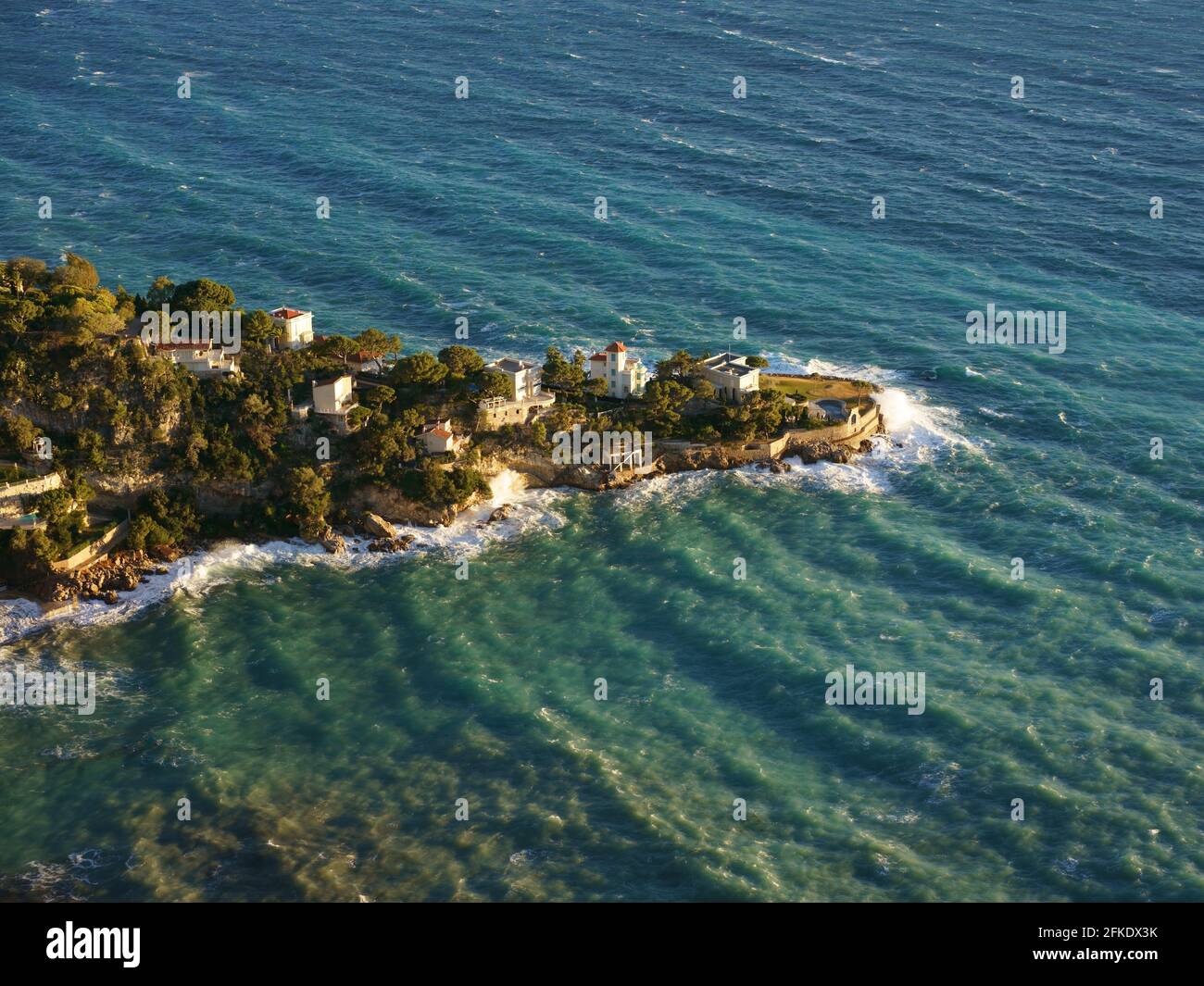 Low angle of the winter sunlight over the choppy Mediterranean Sea and the Luxurious villas of the Mala Promontory. Cap d'Ail, French Riviera, France. Stock Photo