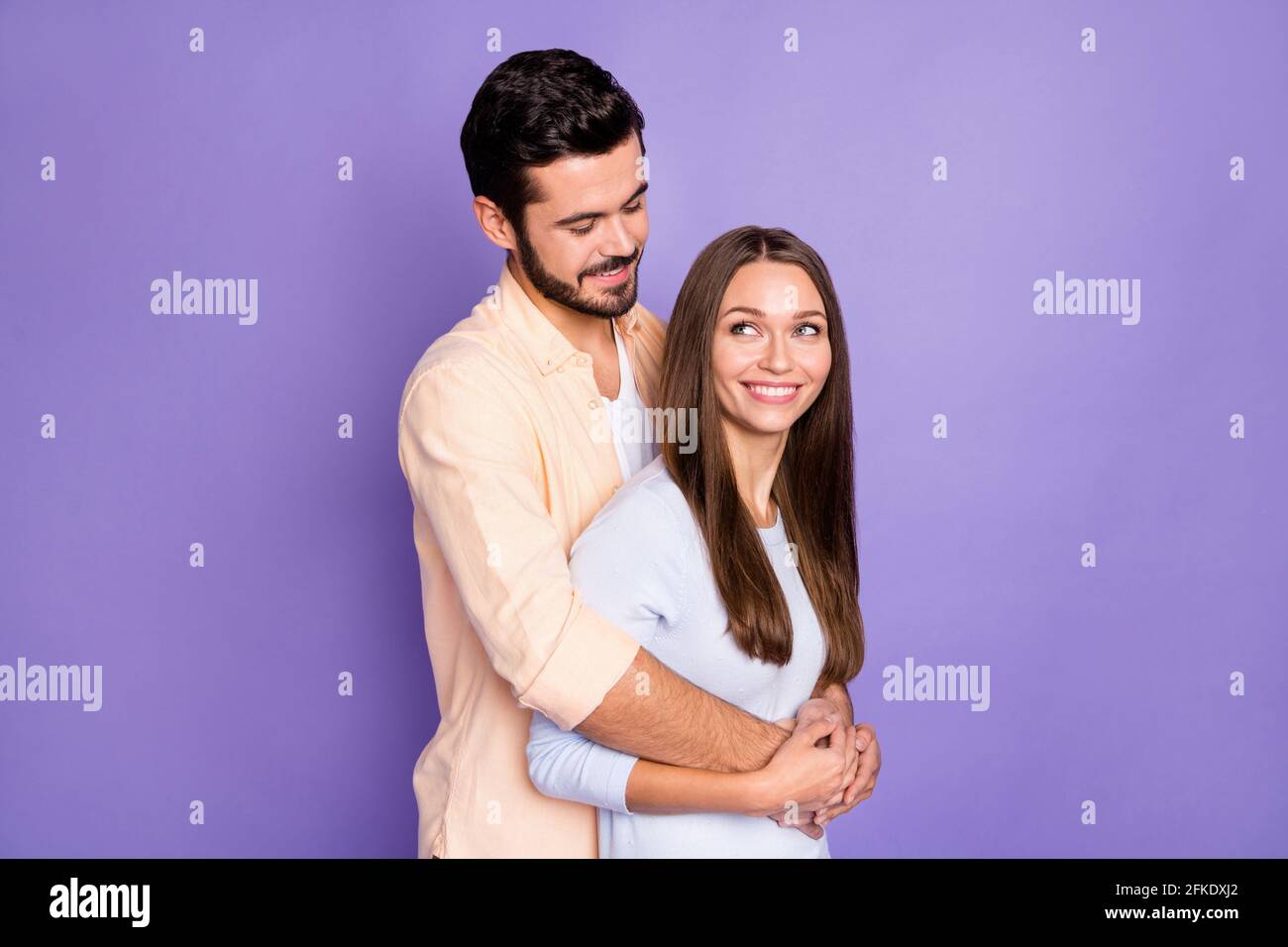 Photo of brown haired man and woman hug look each other wear casual outfits isolated on purple color background Stock Photo