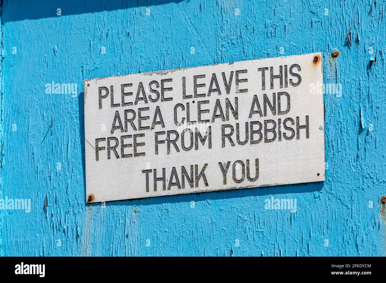 An old worn sign saying do not leave rubbish on a blue wooden wall. Stock Photo