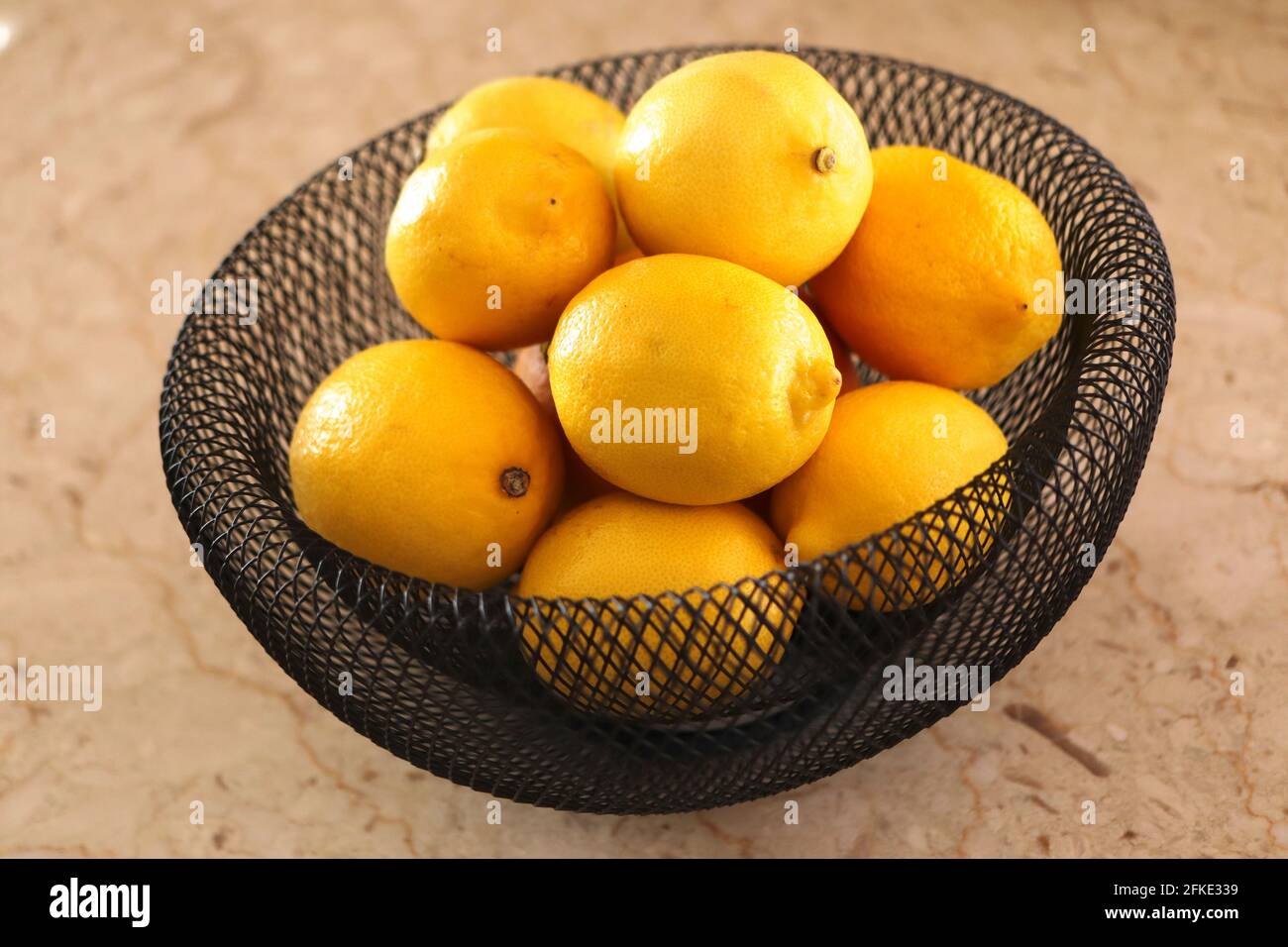 Bunch of yellow lemons in black wire basket Stock Photo