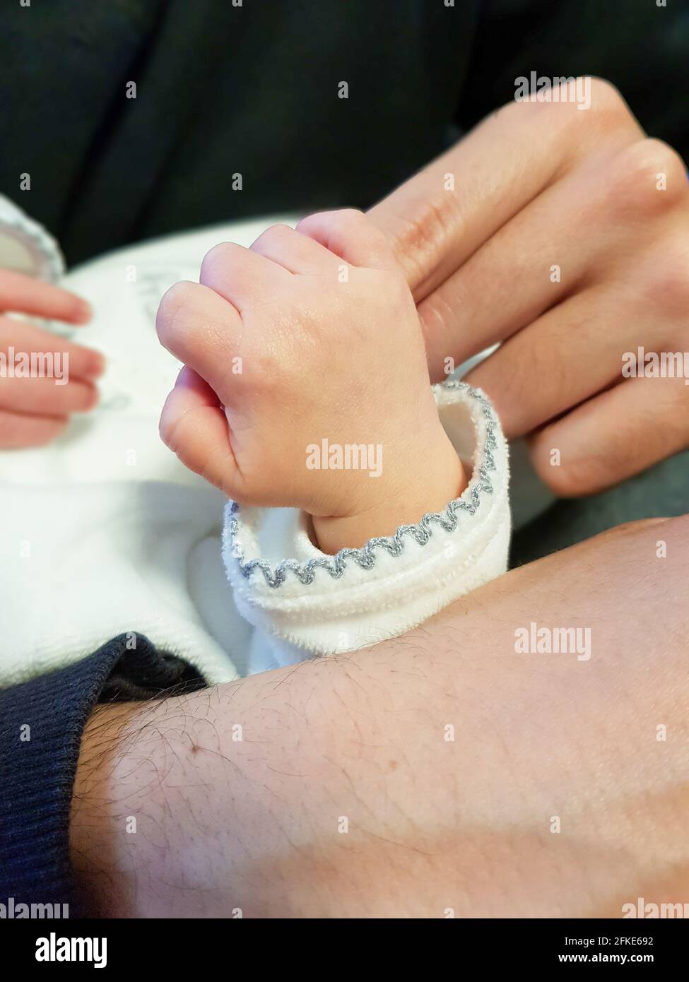 Newborn baby grasping the fingers of an adult Stock Photo