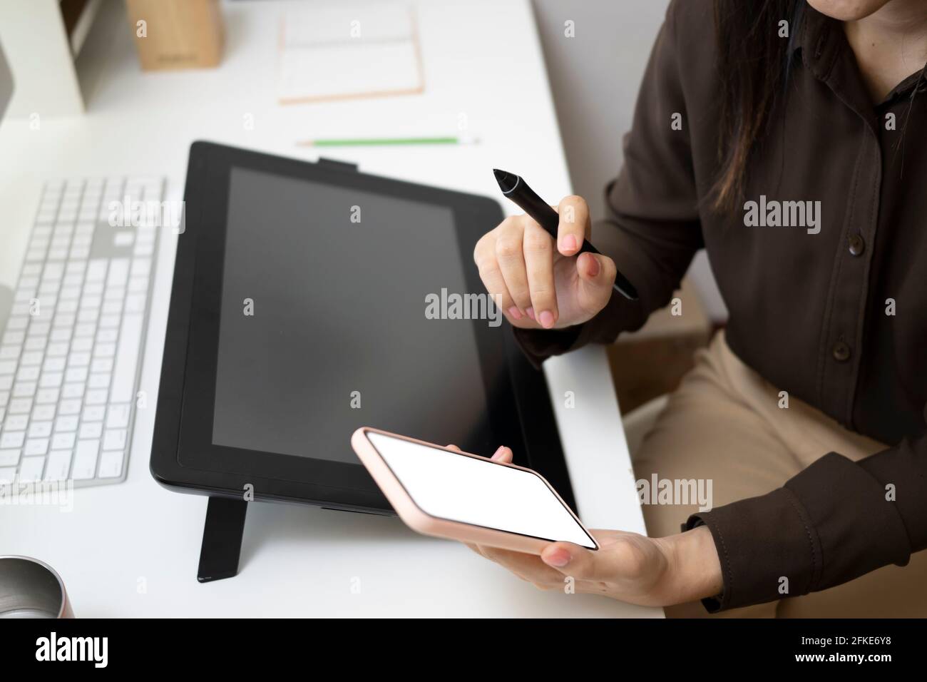 Cropped shot of graphic designer woman sitting at her creative workplace and using mobile phone. Stock Photo