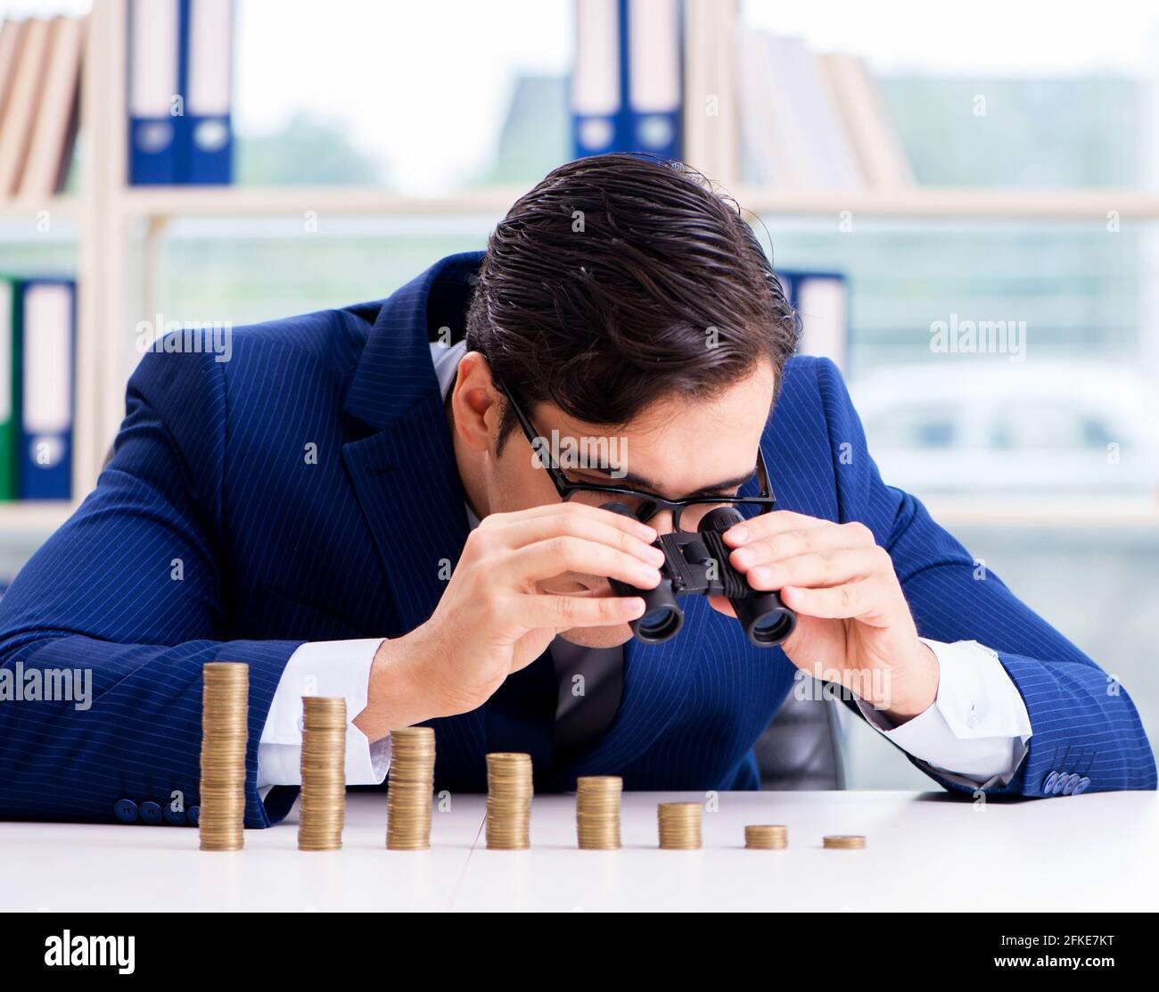 The businessman with stacks of coins in the office Stock Photo - Alamy