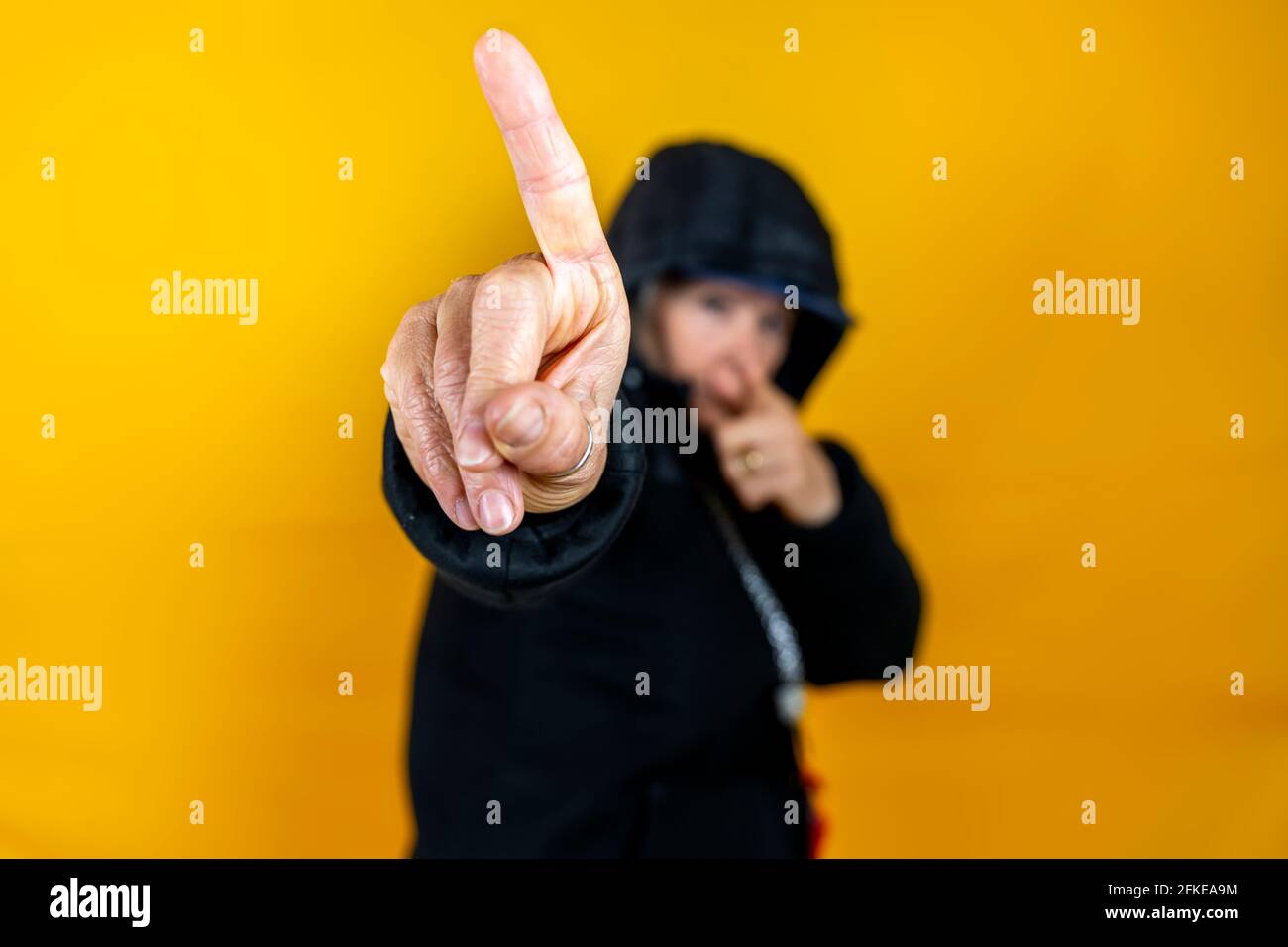 Funny portrait of mature woman. Lady having fun dressed as an angry rapper. Mature woman on colored backgrounds Stock Photo