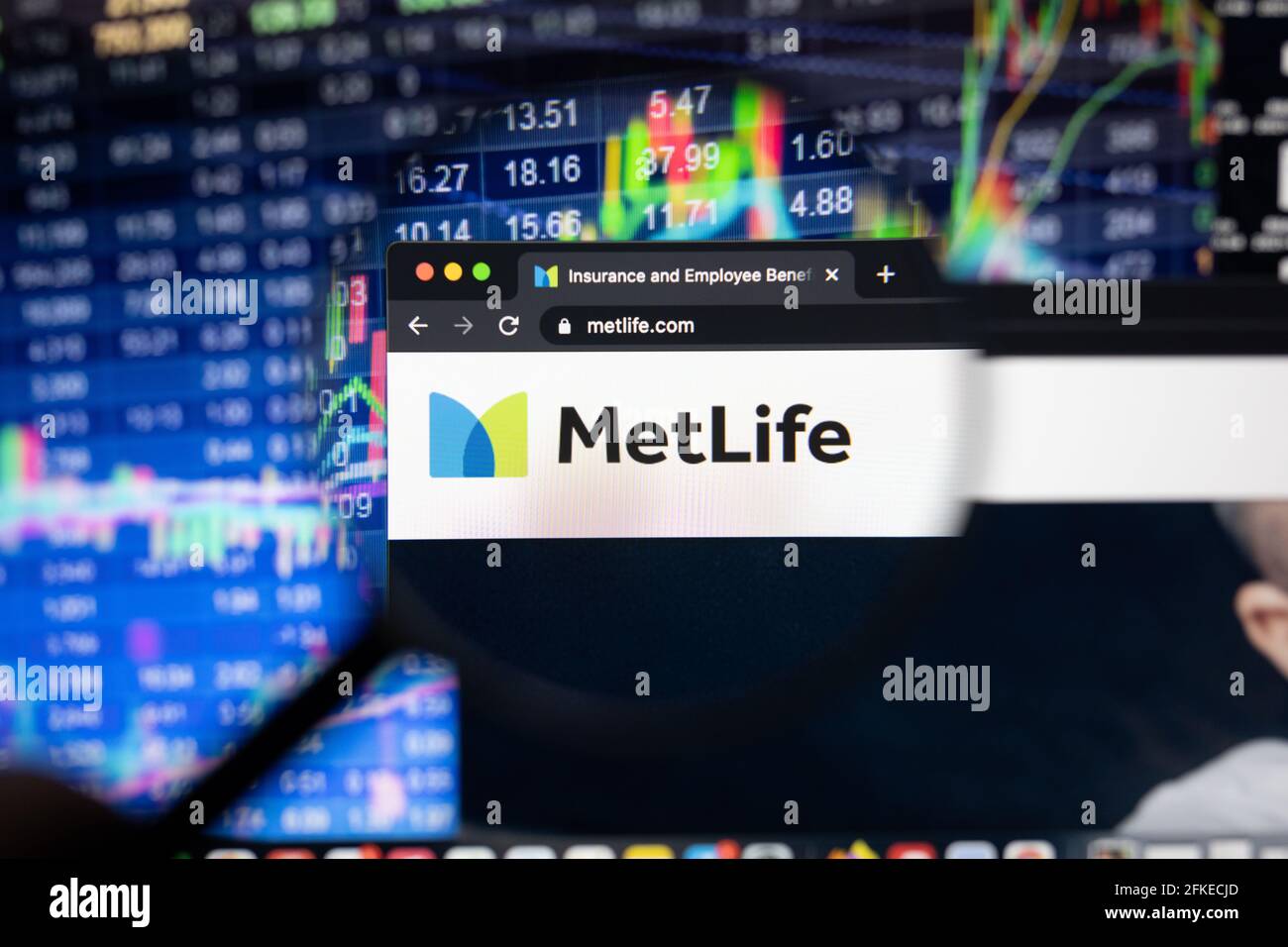 MetLife company logo on a website with blurry stock market developments in the background, seen on a computer screen through a magnifying glass Stock Photo