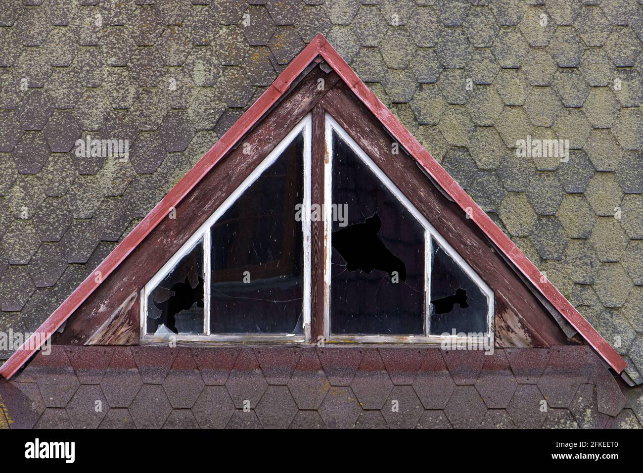 The dormer with damaged glass in the windows on a older roof. Stock Photo