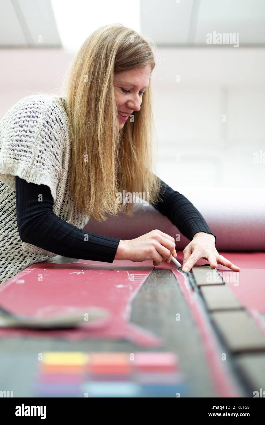 Portrait of a Caucasian woman marking with chalk on fabric a piece to