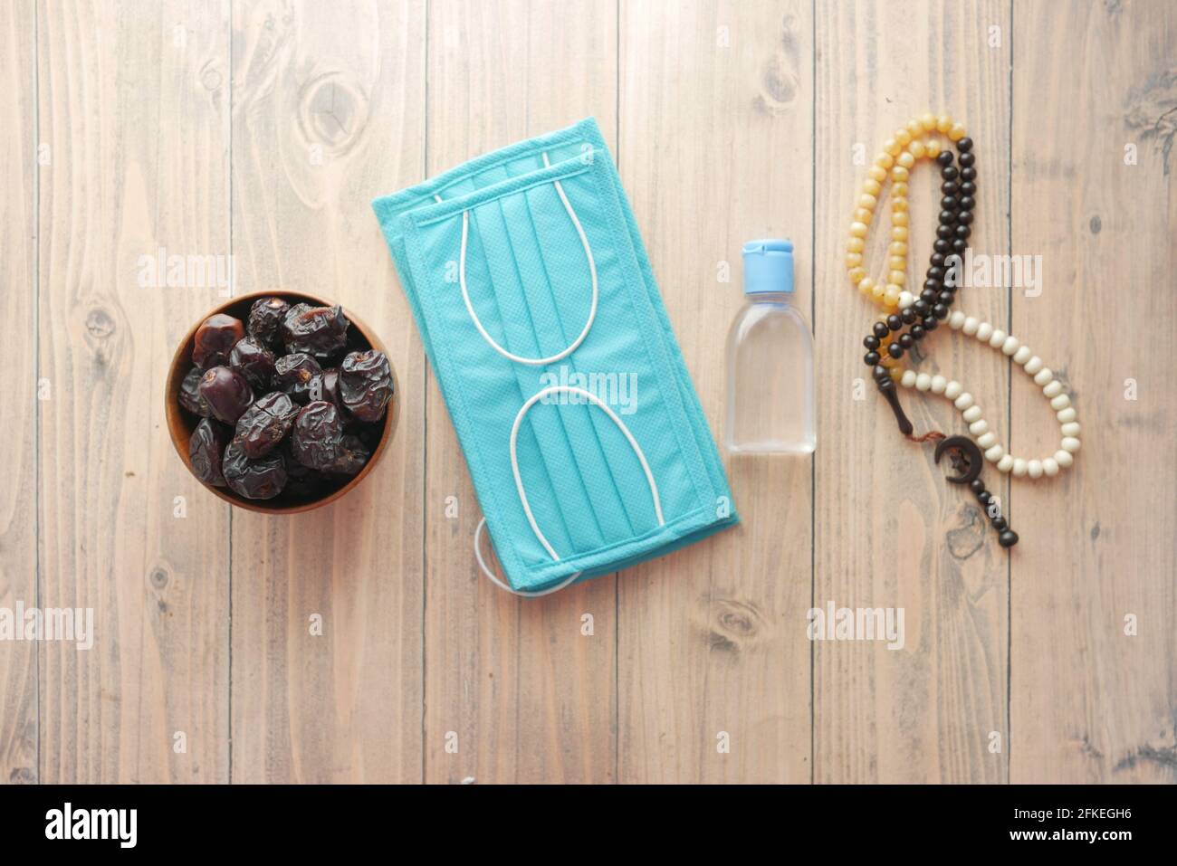 fresh date fruit in a bowl , prayer rosary , hand sanitizer and mask on floor  Stock Photo