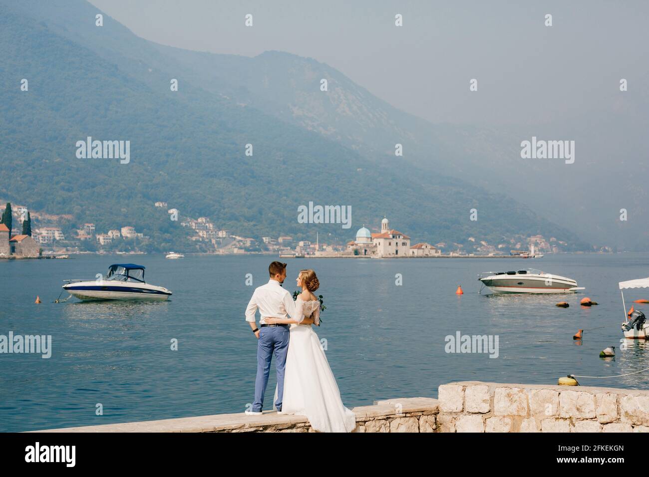 The bride and groom are embracing on the pier near the old town of ...