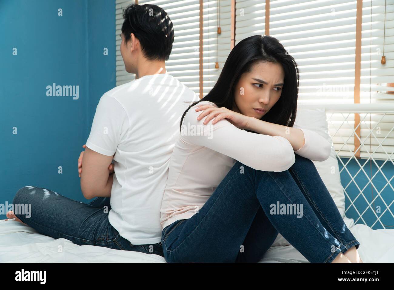 Unhappy Couples Sitting Behind Each Other On The Bed And Avoid Talking