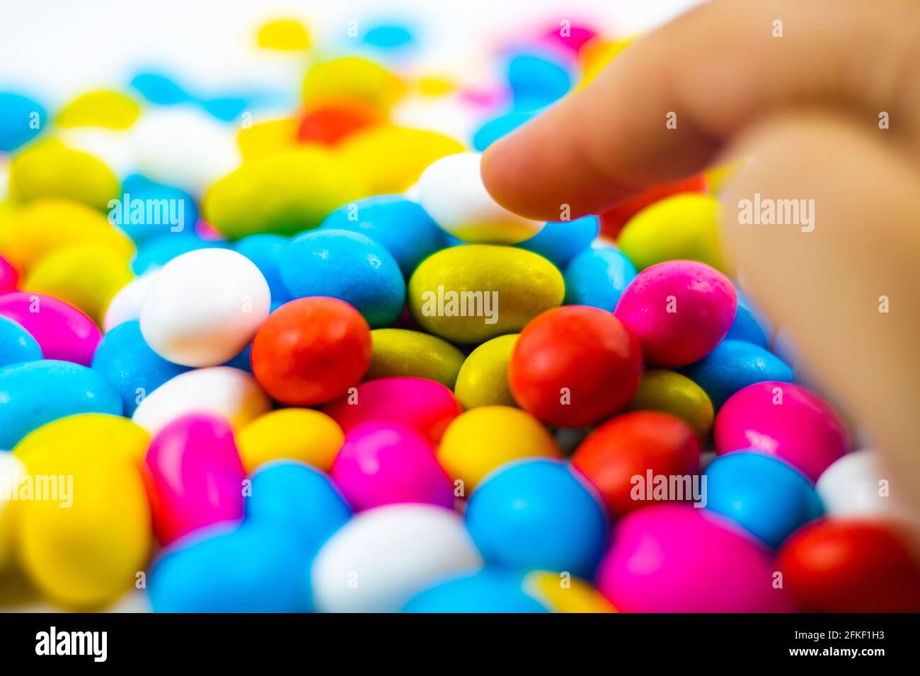 Woman picking a candy in candy bowl in focus on white background Stock