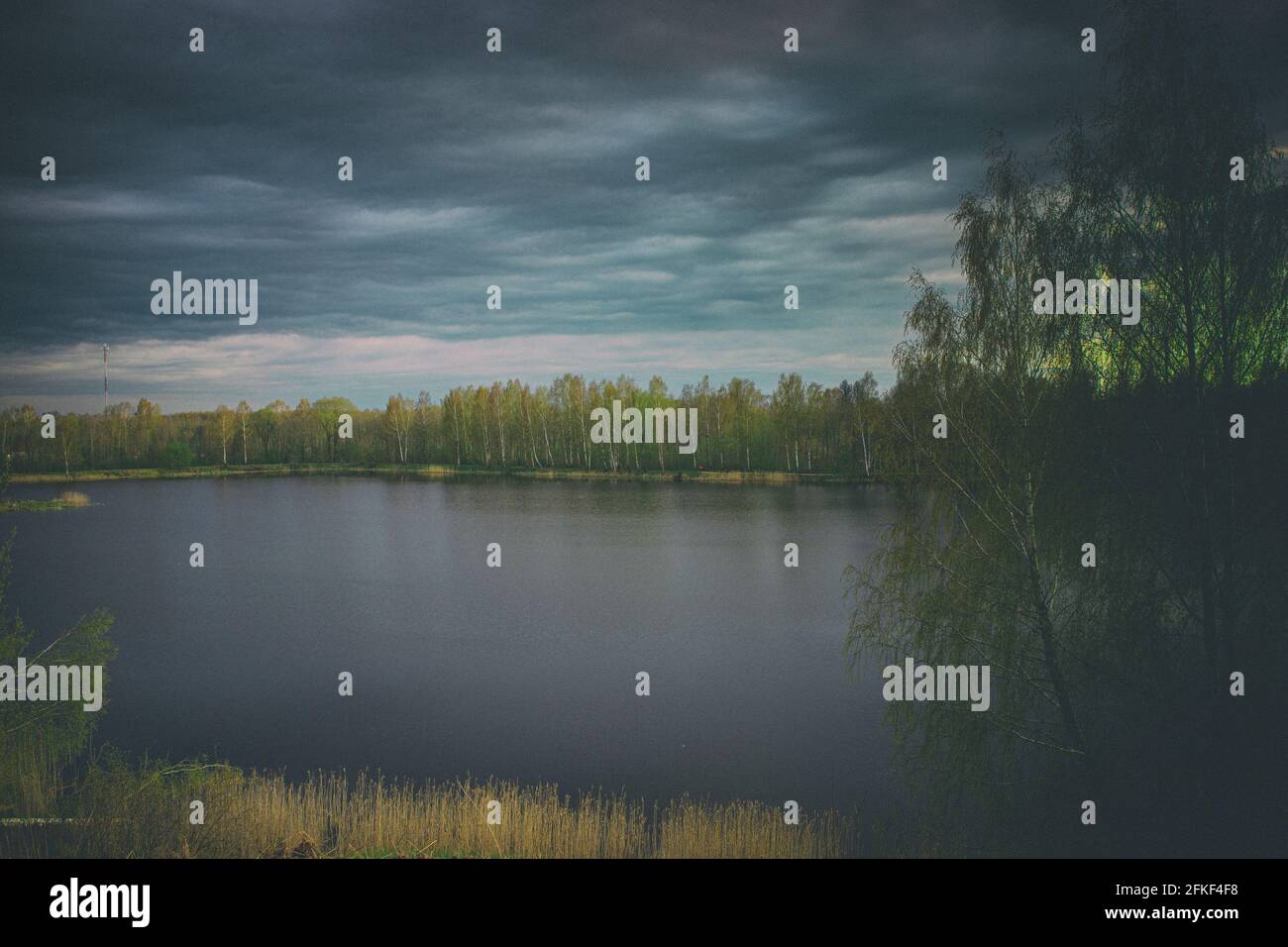 Forest lake view, smooth surface of a lake with clouds reflected, shining level of a forest lake. vintage version, old style photography Stock Photo