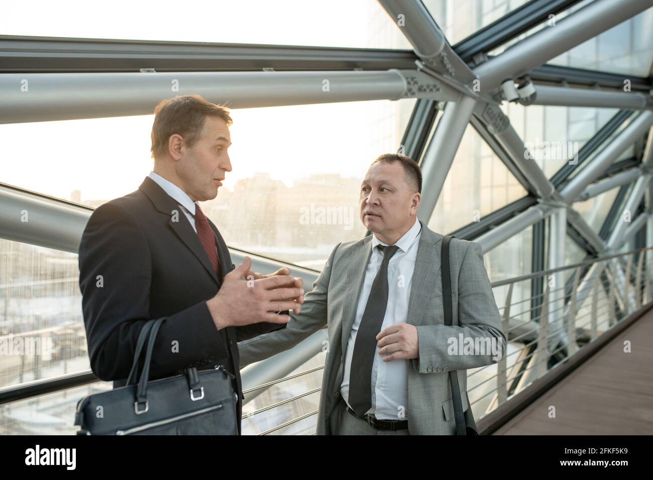 Two mature confident businessmen in suits talking in a server room Stock Photo