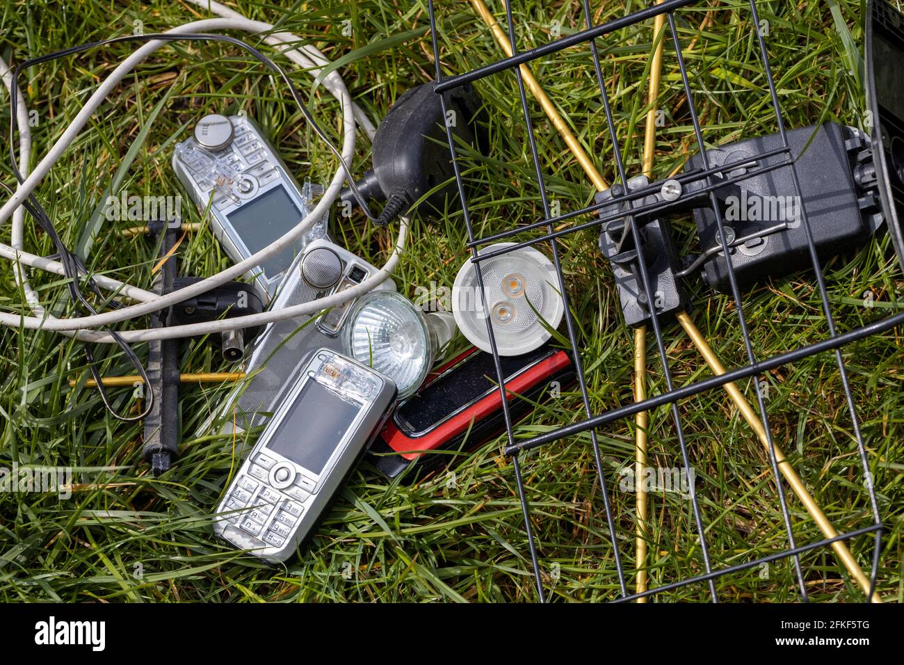 Electro-waste, Old telephones, LEDs, chargers, cables scattered in the grass. The problem of littering and degradation of the environment, old or used Stock Photo
