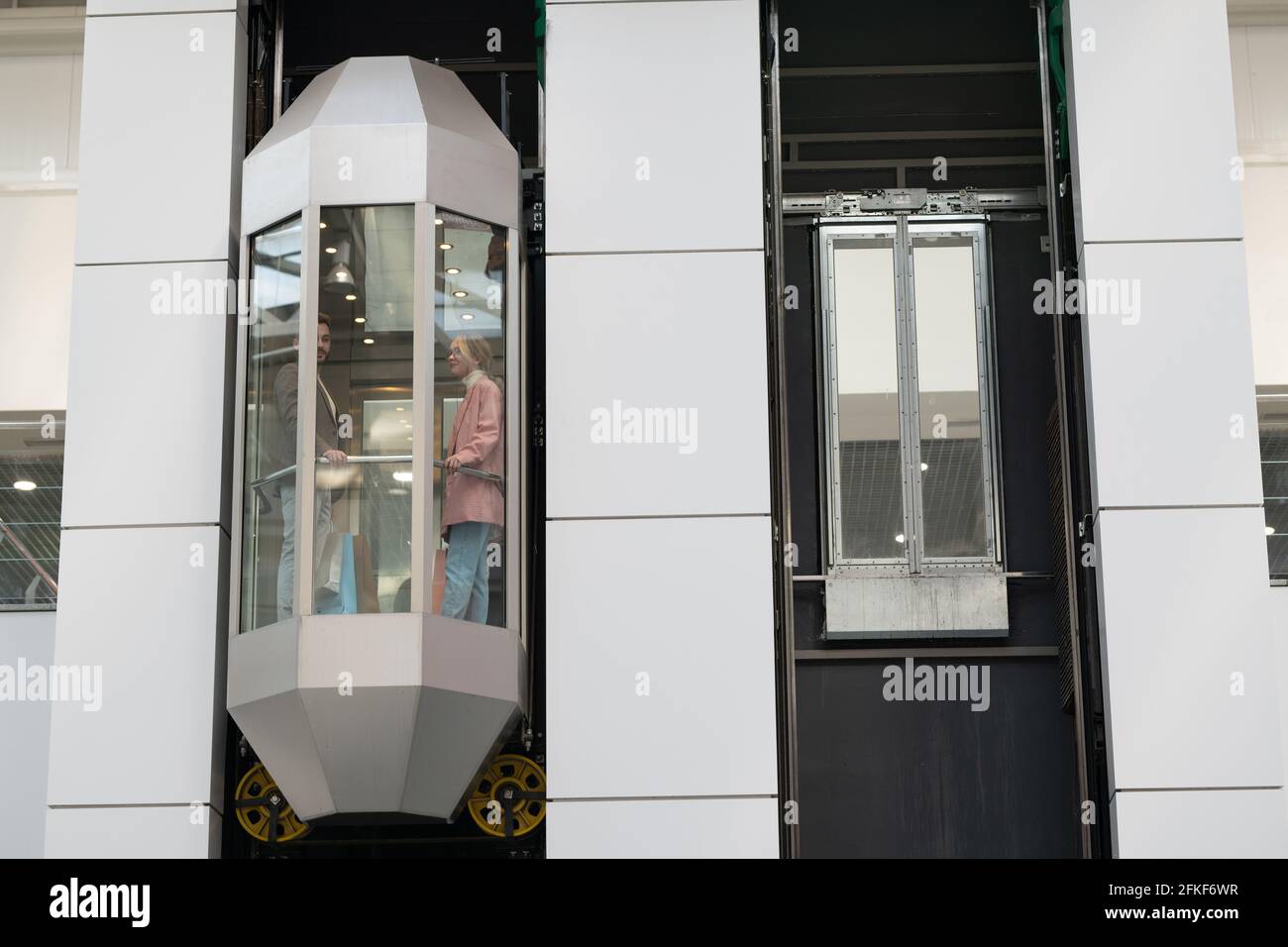 A person standing in moving elevator inside large contemporary mall
