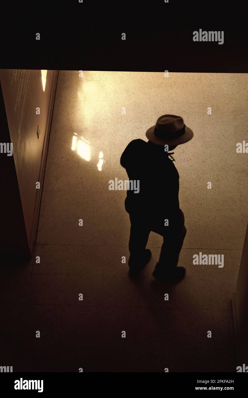 A mysterious figure in a Panama hat emerges out of the shadows and into the sunlight in London, UK Stock Photo