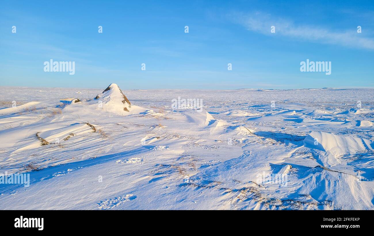 Arctic tundra in northwest territories over a rocky snow covered landscape on a clear cold day Stock Photo