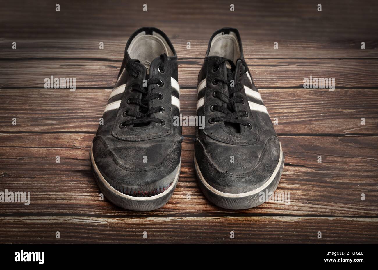 Dirty old black sneakers isolated on a wooden plank background Stock Photo  - Alamy