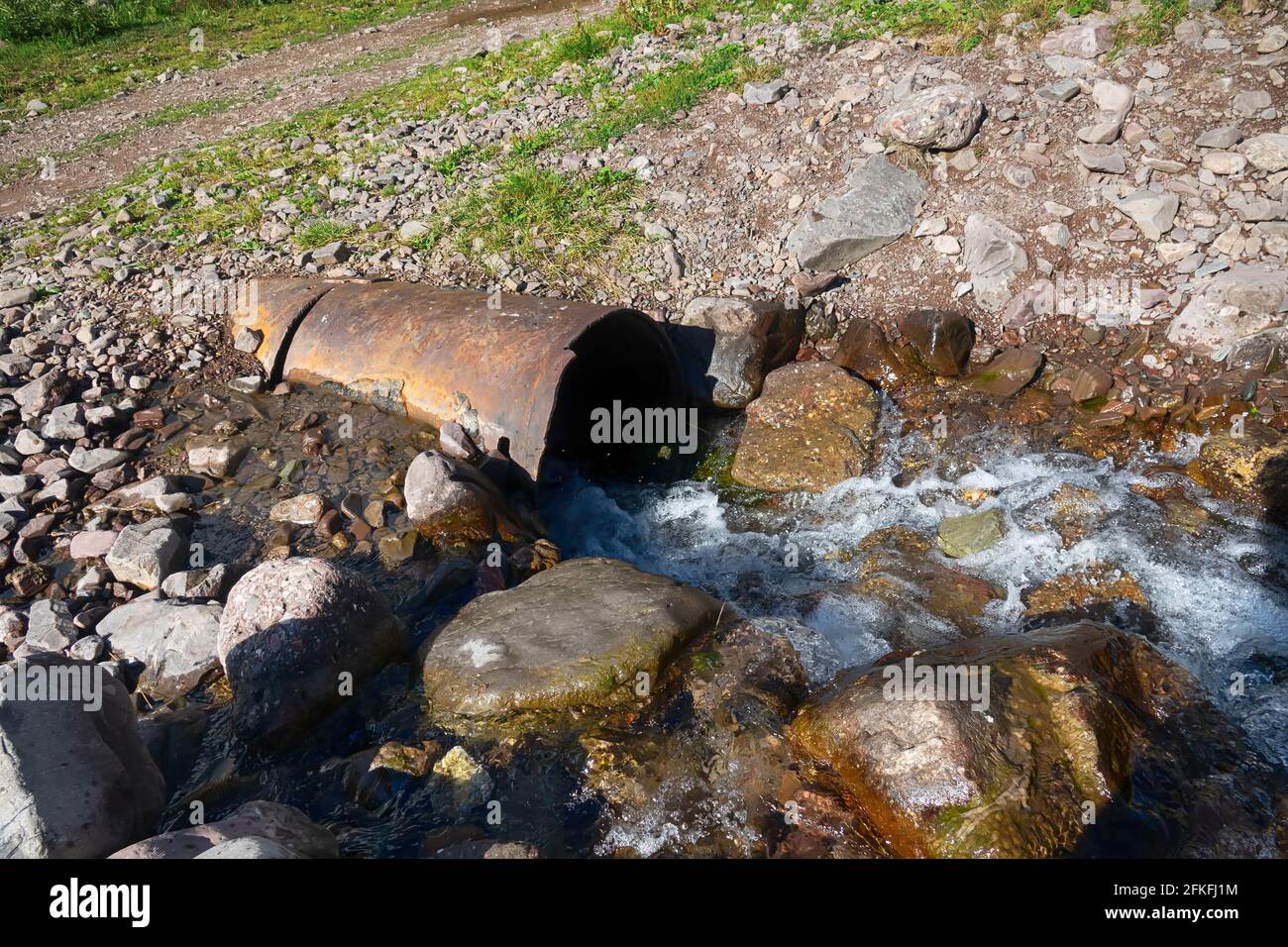 Road culvert was washed away by the spring waters of the stream. Stock Photo